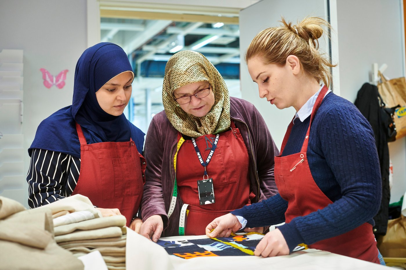 Two co-workers from Yalla Trappan sewing studio in the Malmö IKEA store in Sweden, measuring some fabric.