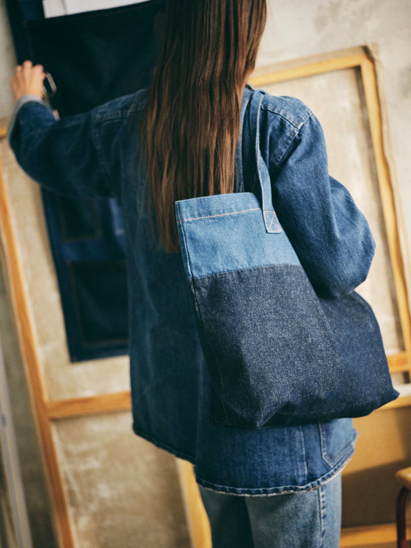 Pereka bentuk Paulin Machado, memakai kemeja denim, menyandang bag MÄVINN.