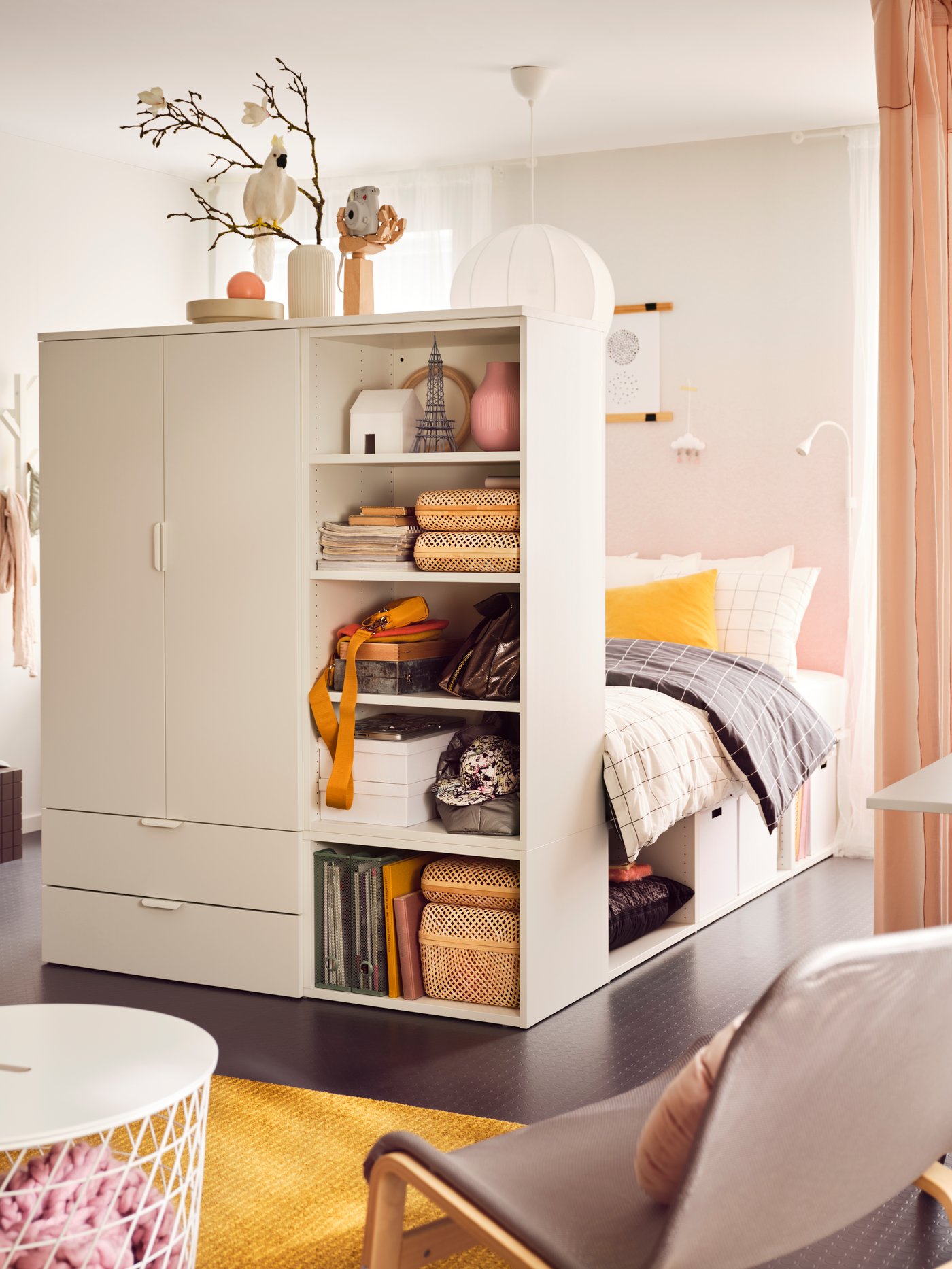 A PLATSA bed with 2 doors + 3 drawers with VITKLÖVER bed linen and boxes, bags and other objects on its shelves.