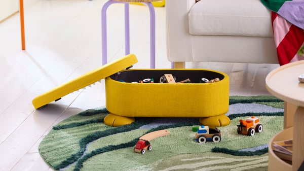 An yellow GREJSIMOJS pouffe with storage in the NA.