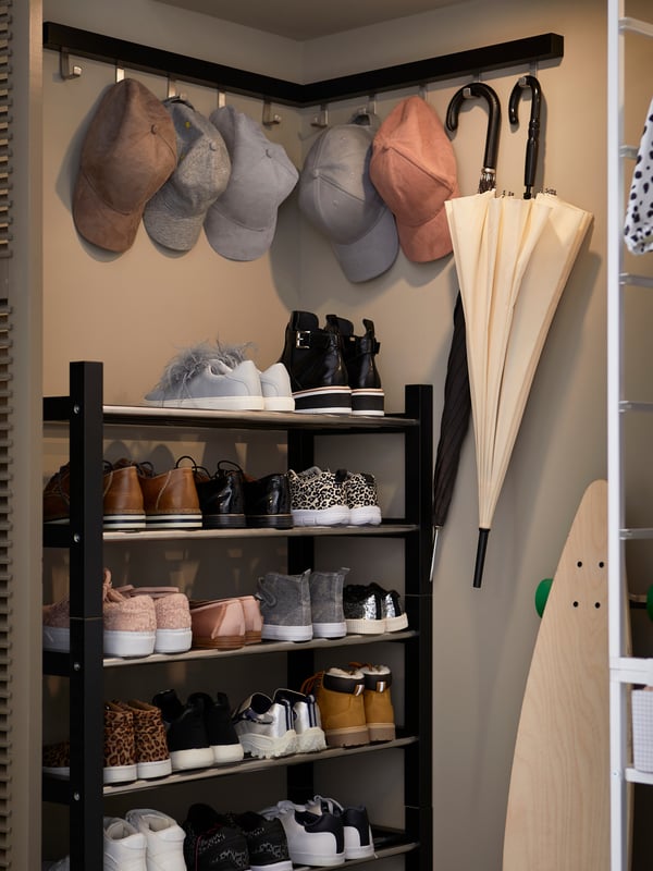 A hallway with garments on TJUSIG vertical hook racks, notes on VATTENKAR wall storage units, and shoes on PINNIG benches.