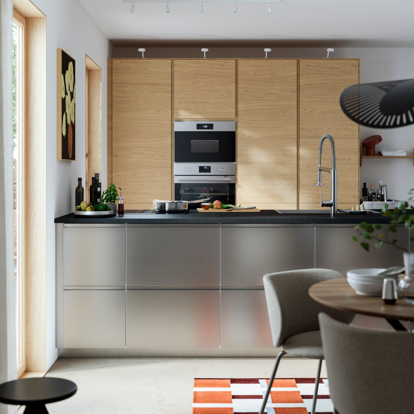 A modern minimalist kitchen where the kitchen island is fitted with VOXTORP stainless steel effect drawer fronts.