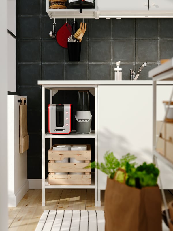 An ENHET base frame with shelves in white, with ENHET legs in white, holding a KNAGGLIG box in pine and various other items.