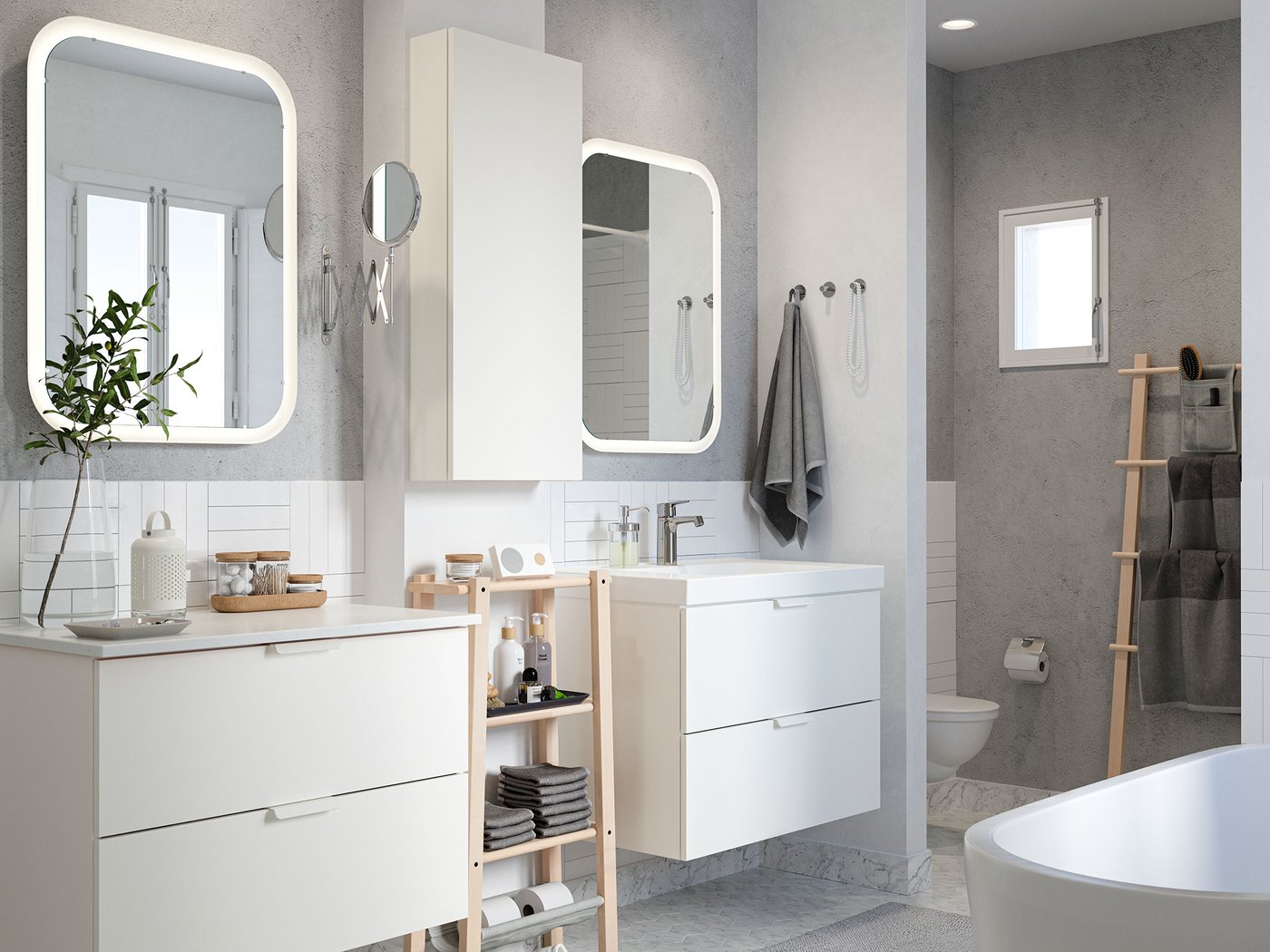 Baño con azulejos blancos, paredes grises, dos lavamanos, espejos y un estante de abedul con toallas y productos de belleza.