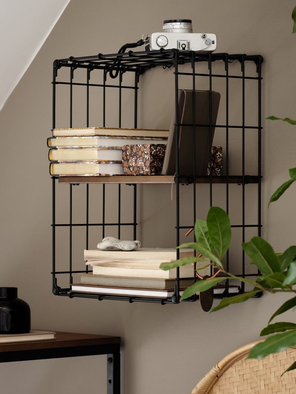 Une étagère murale noir/pin à l’aspect ancien avec des livres, un appareil photo, une boîte et une pierre.