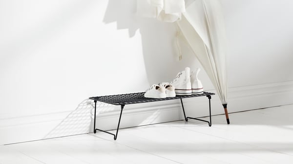 GREJIG shoe rack next to a white wall with a white umbrella standing next to it.