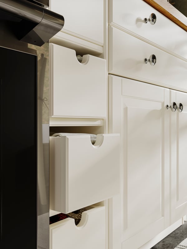 Shelves holding TORNVIKEN boxes in off white, BODBYN doors and drawer fronts in off-white and ENERYDA chrome plated knobs.