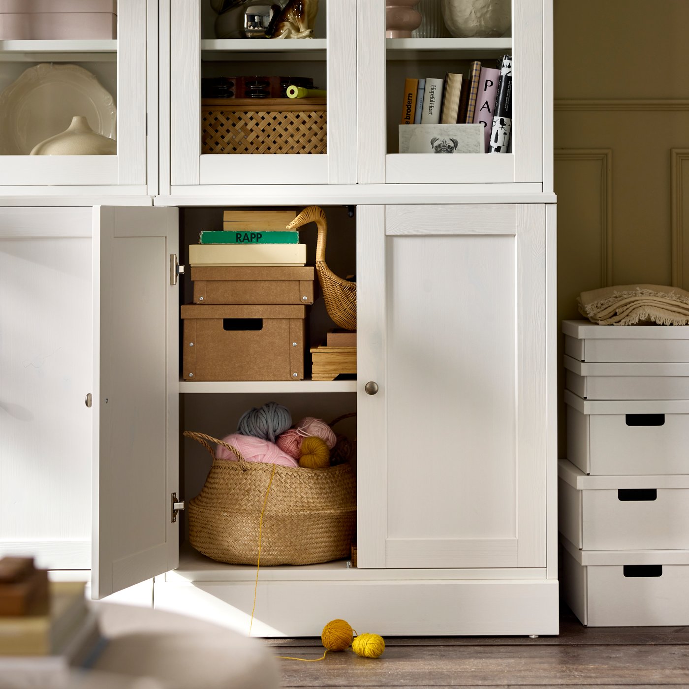 A black HAVSTA storage combination with one cabinet door open, revealing stacked boxes and a basket of knitting accessories.