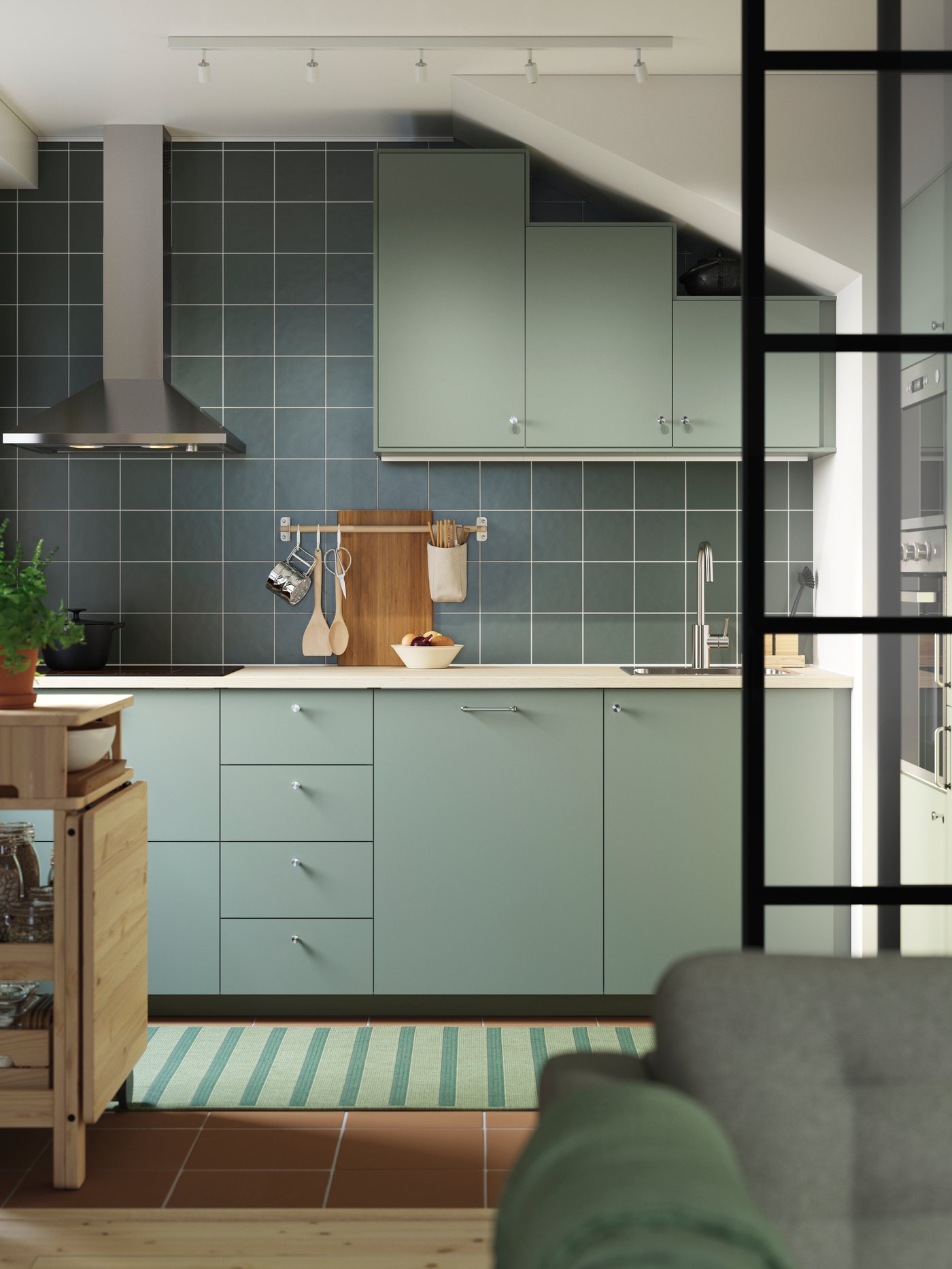 A grey green NICKEBO kitchen has base cabinets and wall cabinets under a slanted ceiling and a RESARÖ mobile drop-leaf table.