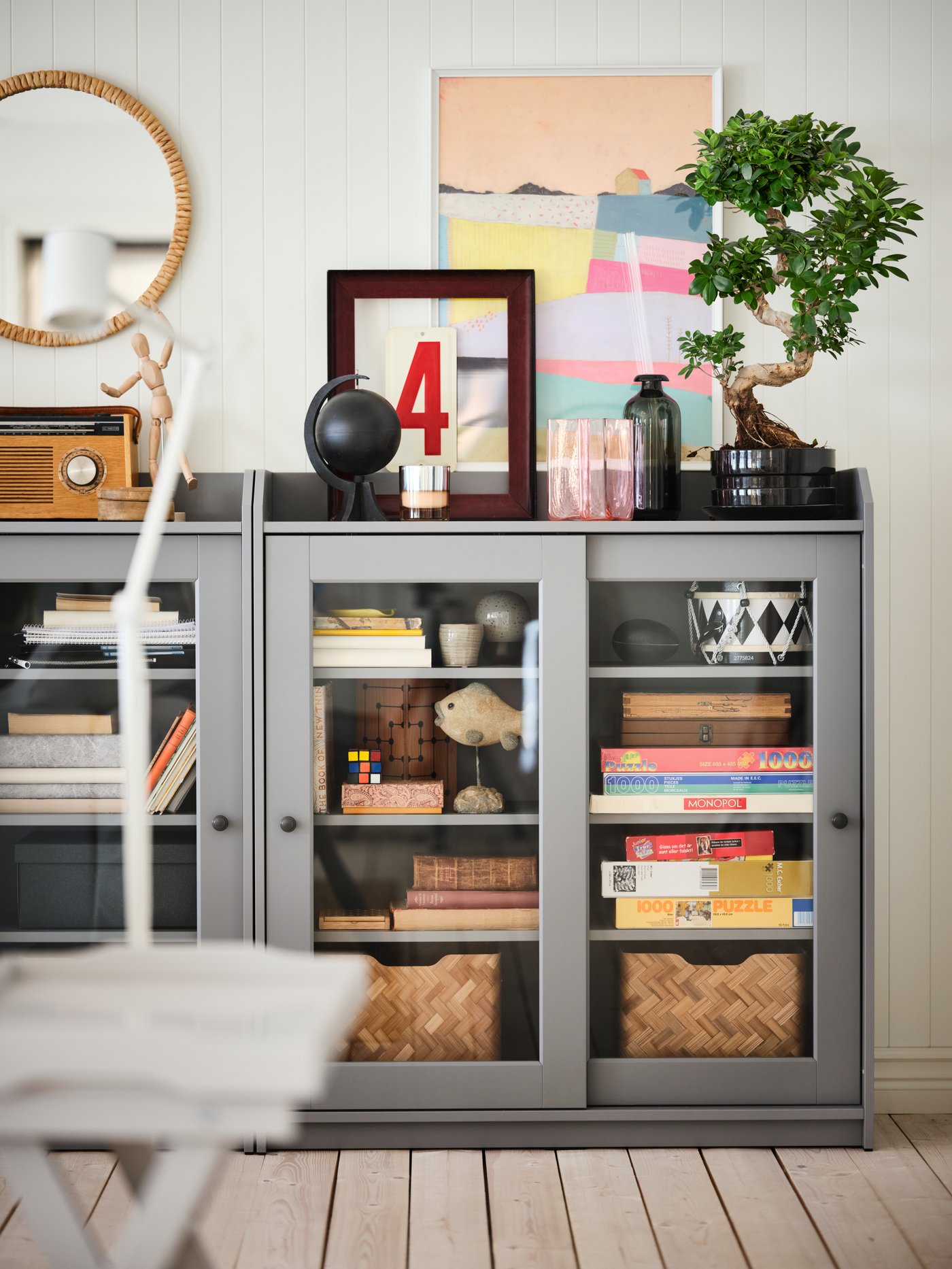 A water hyacinth STAFFANSTORP mirror above a grey low storage cabinet with glass sliding doors