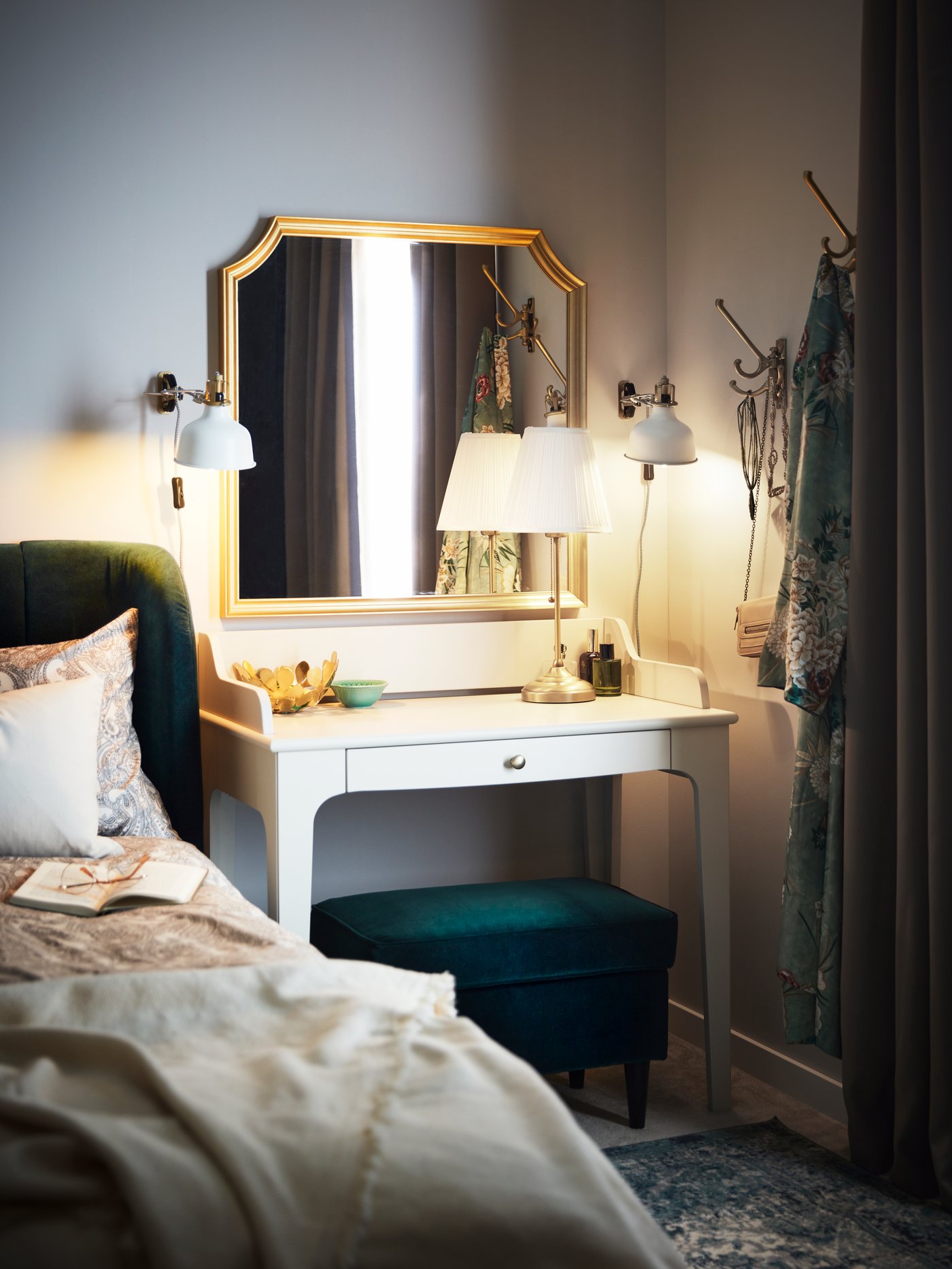 Una habitación con un tocador LOMMARP al costado de una cama doble .Sobre la mesa hay una lámpara de mesa ÅRSTID encendida.