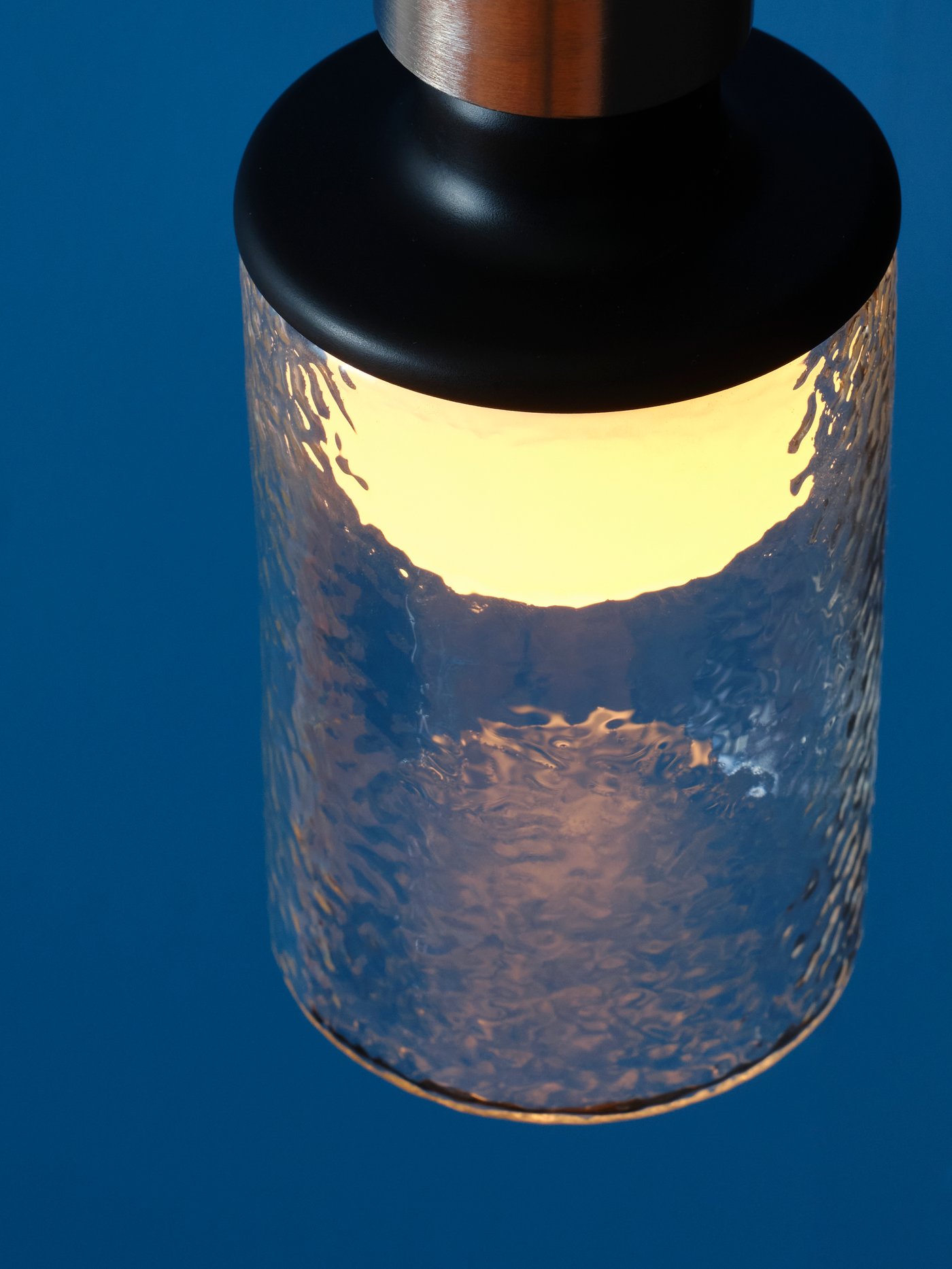 The top of a MOLNART tube-shaped, patterned-clear-glass LED bulb, shown against a dark blue background.