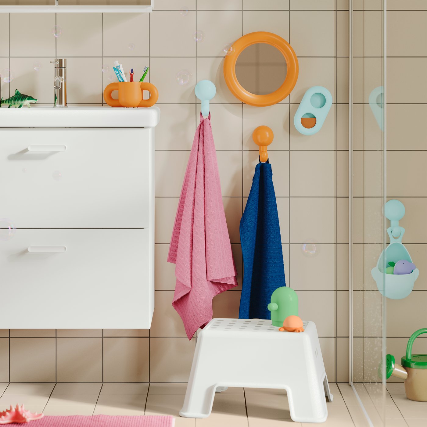 Un taburete BOLMEN en el piso, un lavabo y toallas y accesorios coloridos en la pared a una altura apta para niños.