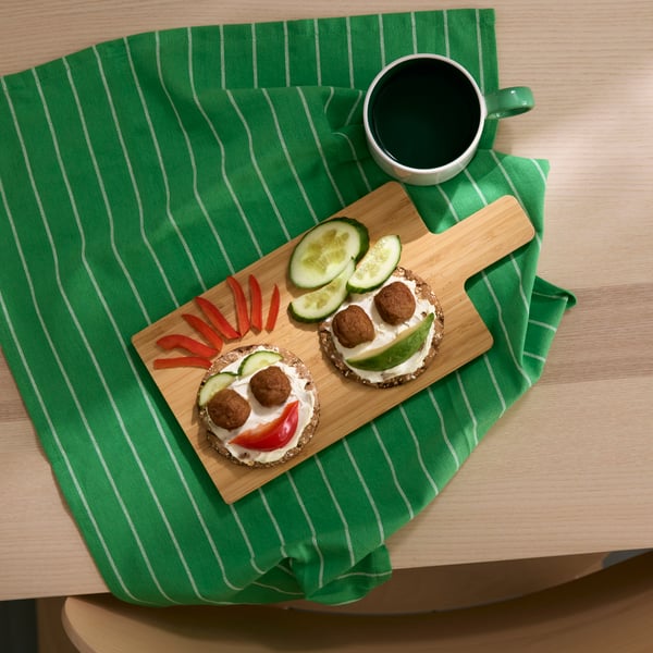 Picture of two pieces of round KNÄCKEBRÖD FLERKORN decorated as faces with vegetables, picture shot from above.