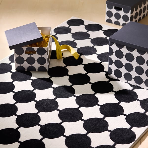 Black and white rug with connected dot pattern and matching storage boxes.