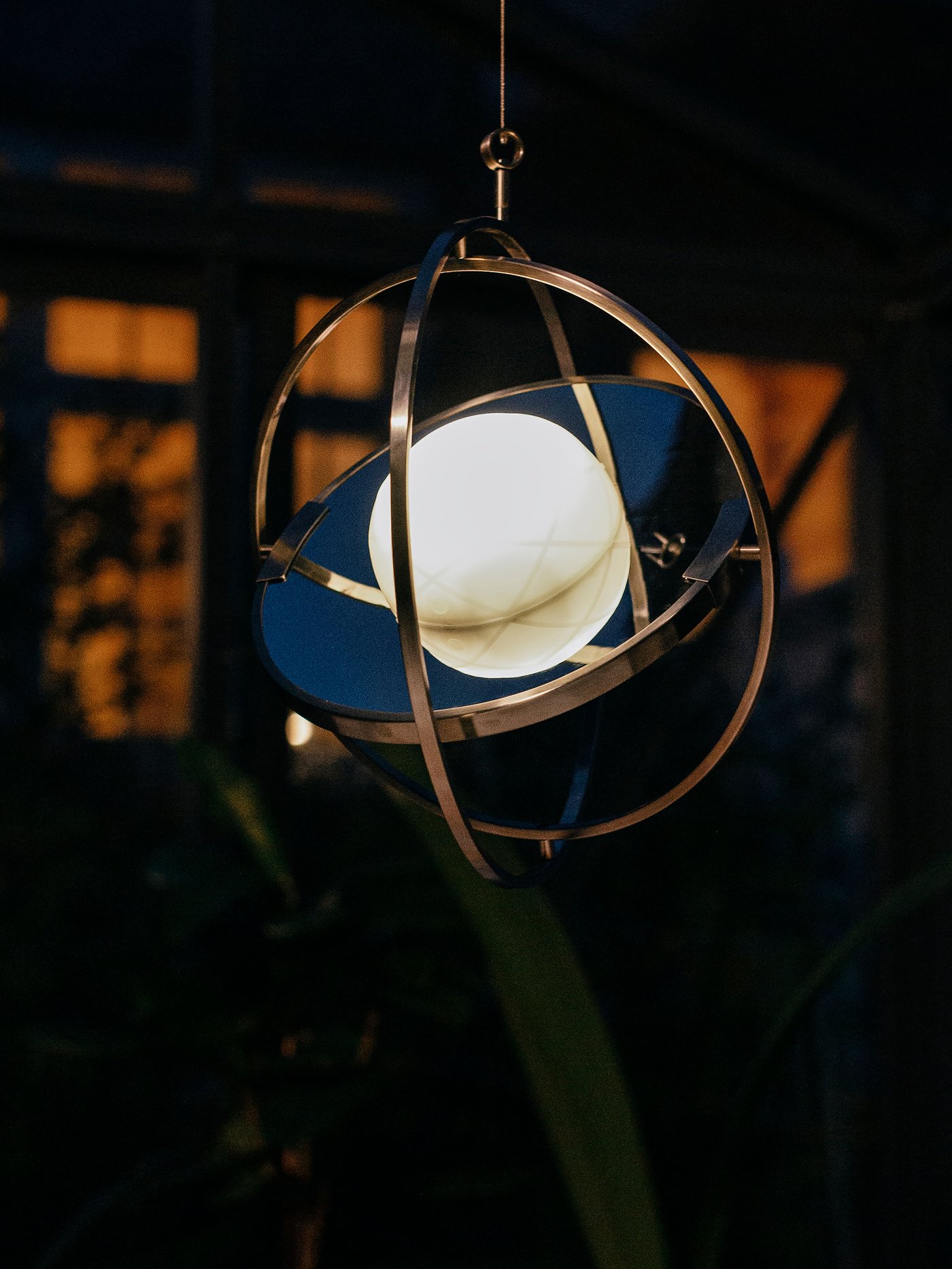 Lampu meja berkuasa solar LED SAMMANLÄNKAD menyala dan digantung di wayar dalam taman yang gelap. Di latar belakang ialah beberapa tingkap.