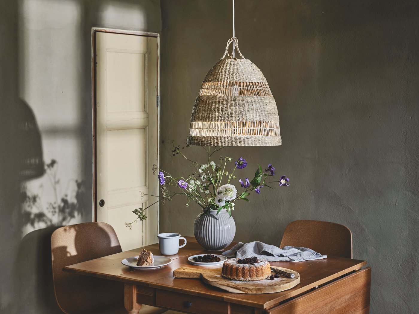 En lantlig matplats med trämöber och blommor i en vas.