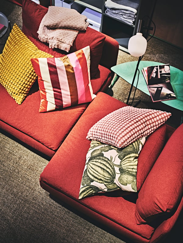 Retro cushions and cushion covers on a red sofa in a living room.