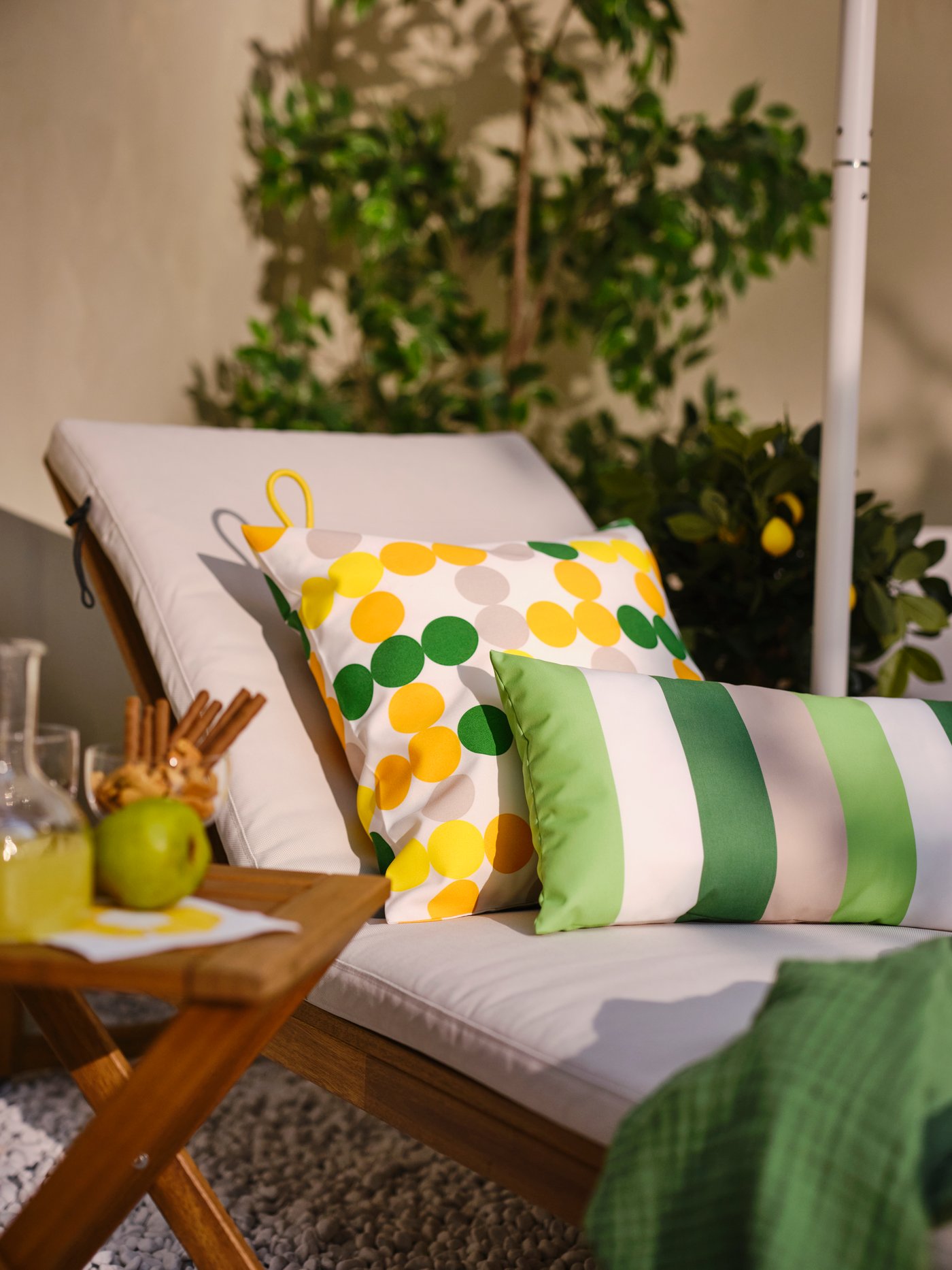 Cushions with BRÖGGAN cushion covers with yellow stripes and floral patterns are hung on a bright yellow wall.