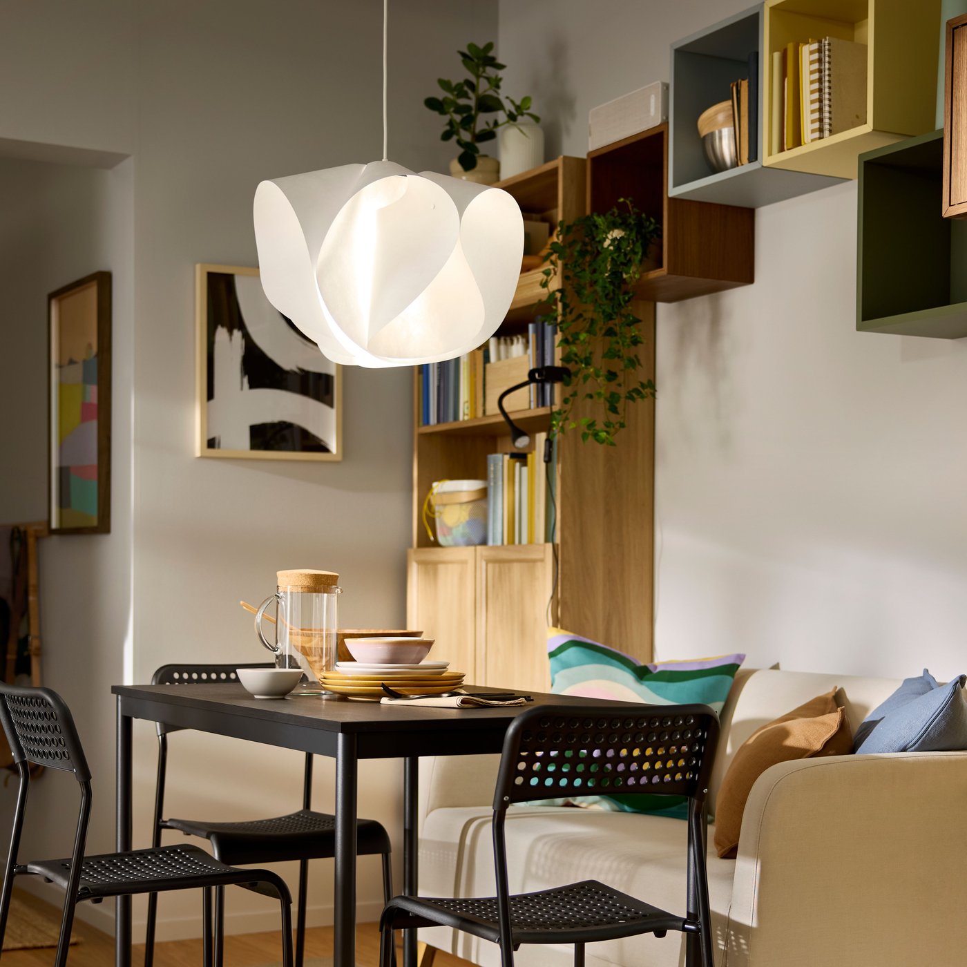 Petit coin repas avec canapé LINANÄS beige, table SANDSBERG noire et trois chaises ADDE noires, et lampe BÄCKNATE.