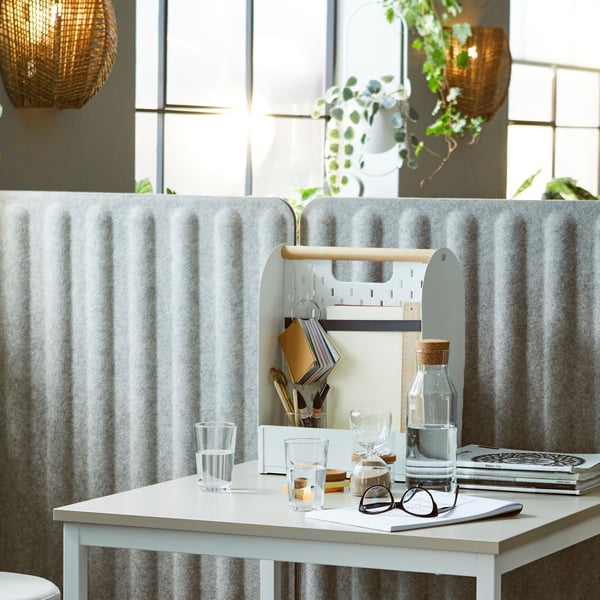 A small workstation with a TROTTEN table, and a VATTENKAR desk organiser portioned off using grey/white freestanding screens.