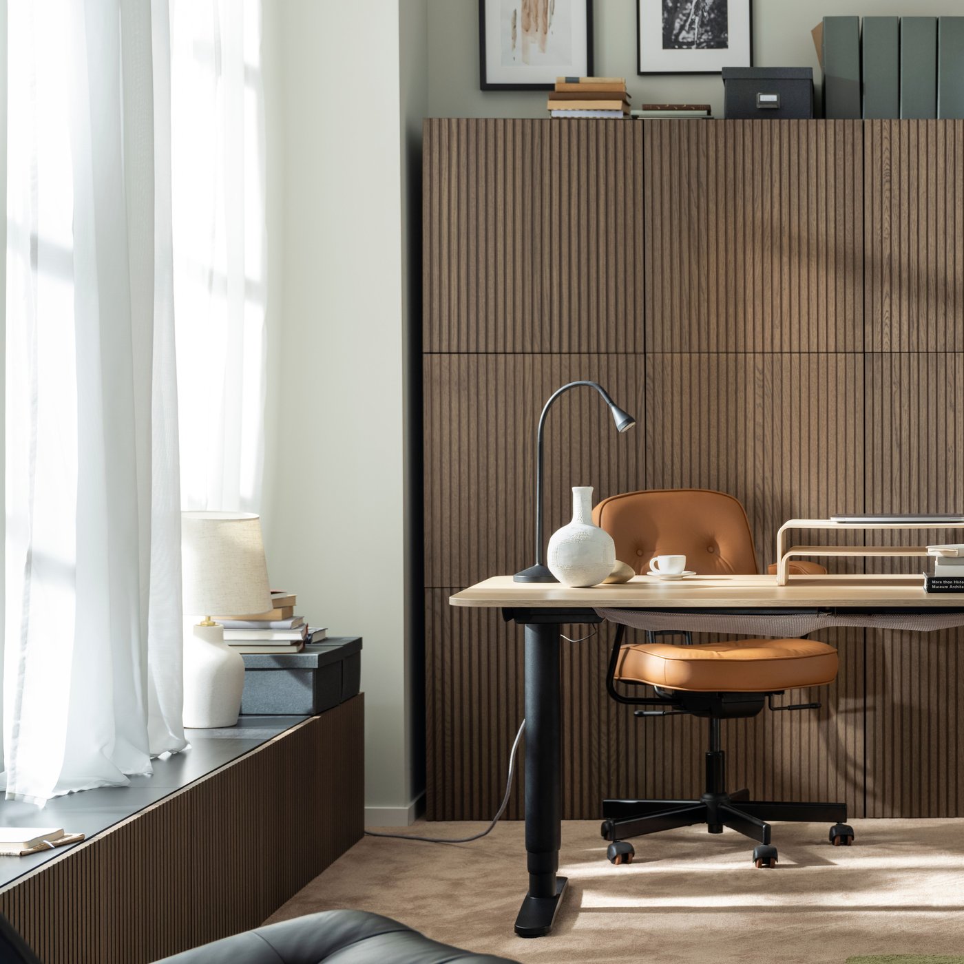 A BESTÅ TV bench and a BESTÅ storage combination, both with BJÖRKÖVIKEN doors, stand in a corner of a room near a desk.