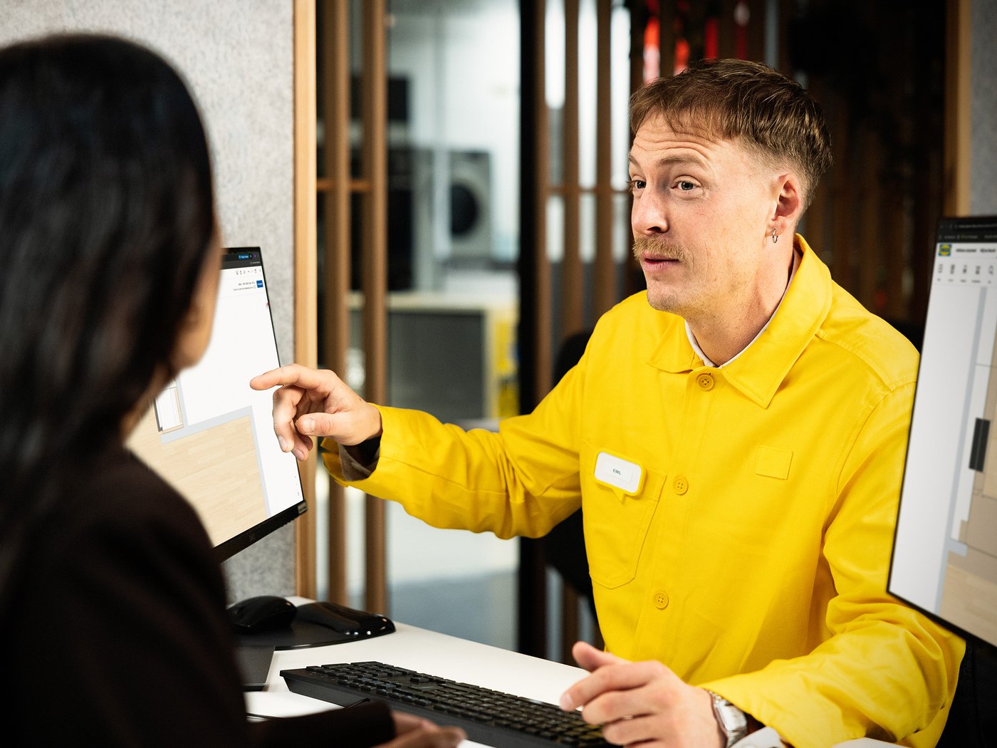Un employé d’IKEA montre une esquisse 3D d’une cuisine à un client.
