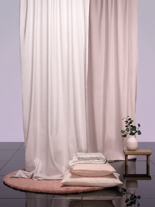 Large HANNALILL curtains drop from the ceiling, over a ÅDUM large round rug in a minimal setting. 