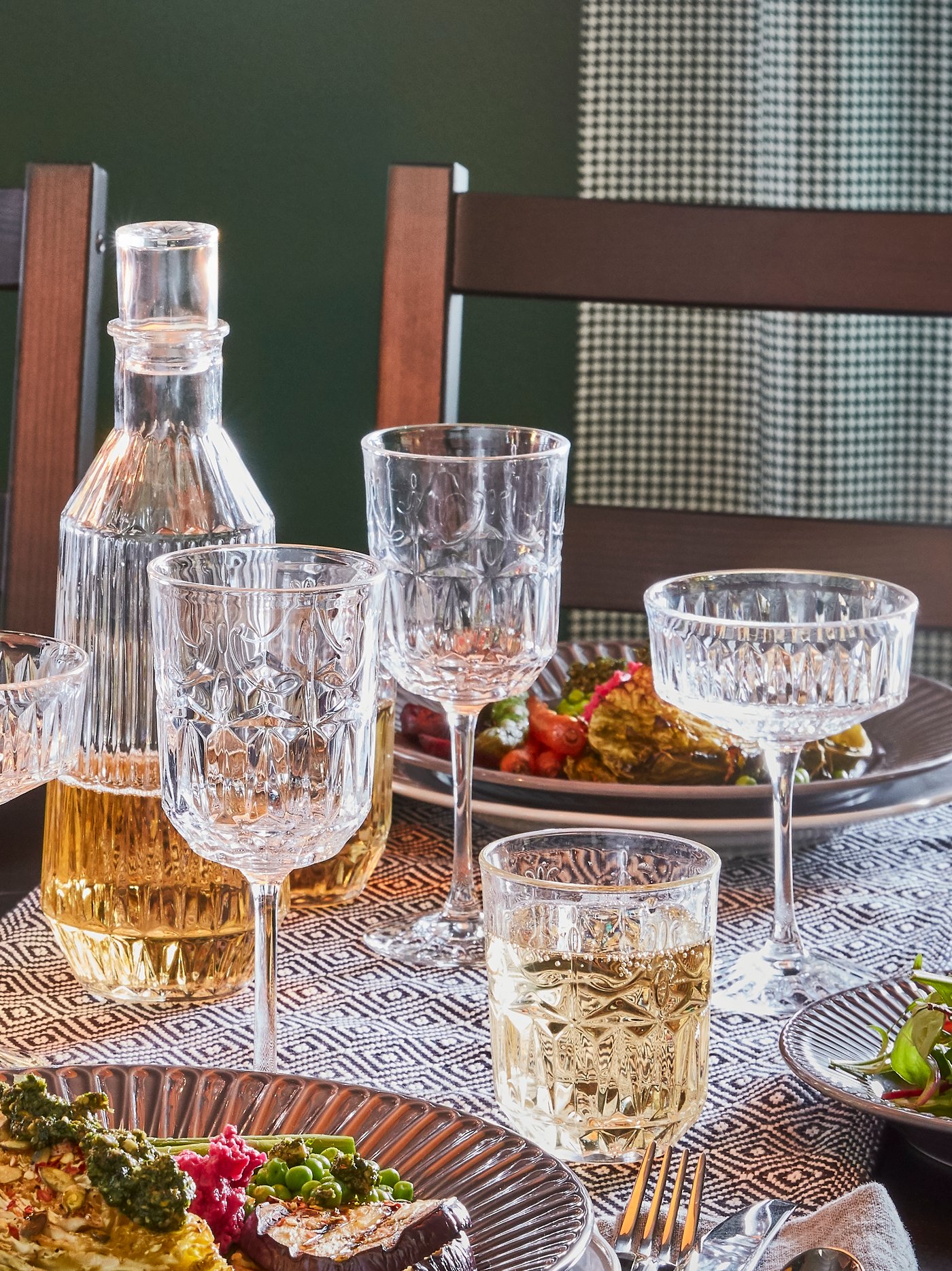 Copas de vidrio SÄLLSKAPLIG en una mesa junto a platos con ensaladas.