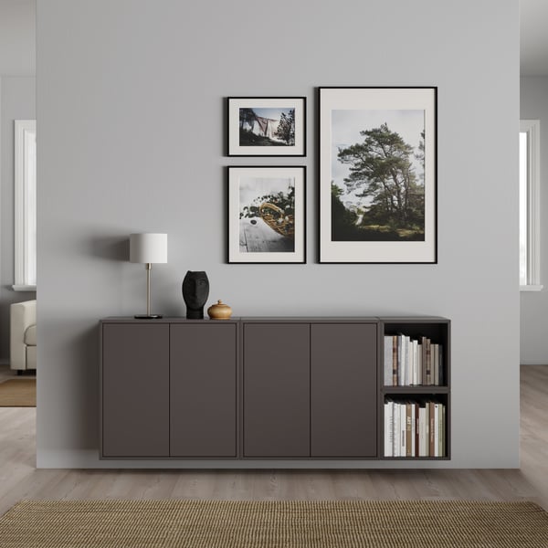 A hanging sideboard in dark gray with pictures above it on the light gray wall.