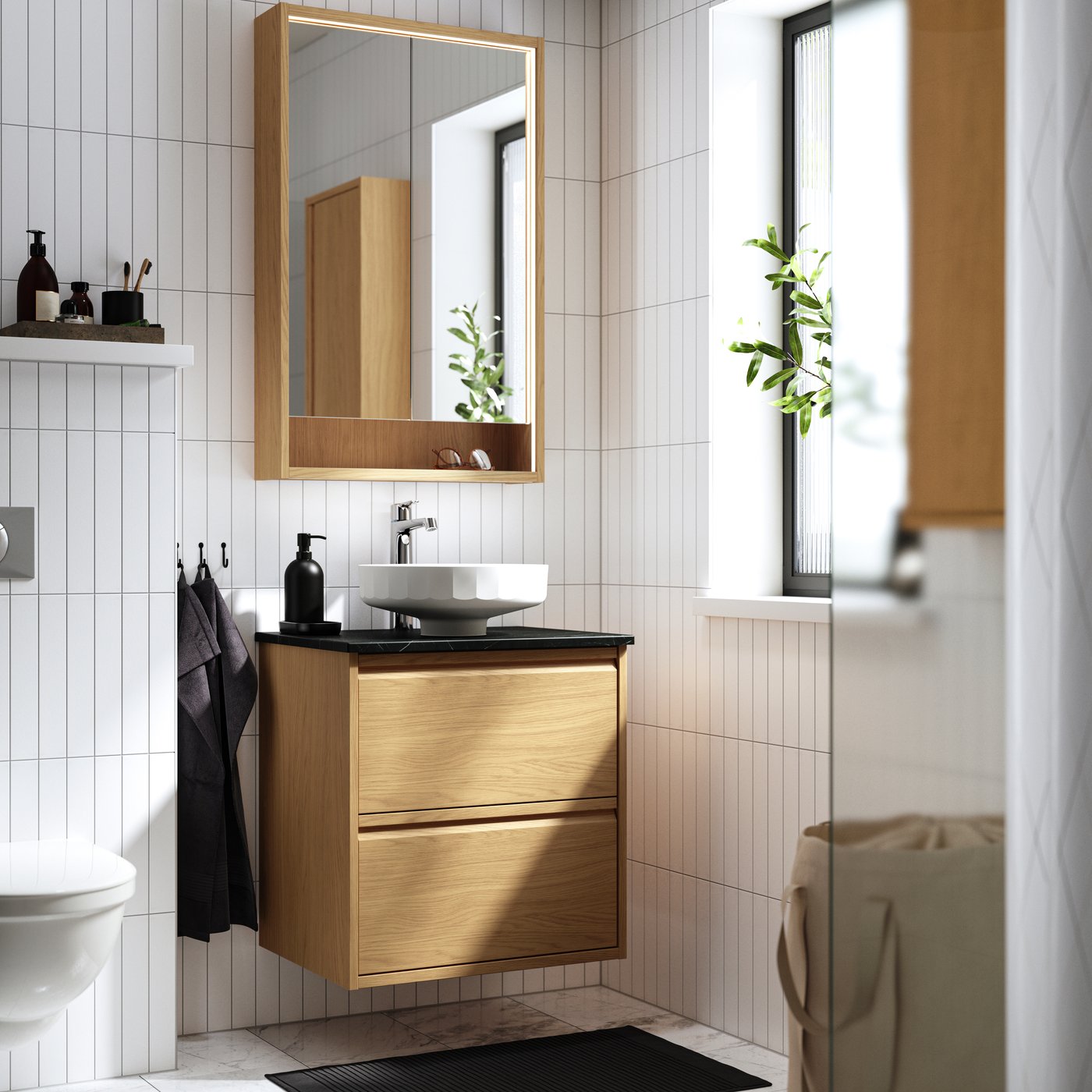 Mueble de baño ÄNGSJÖN anclado a la pared bajo un espejo de baño.