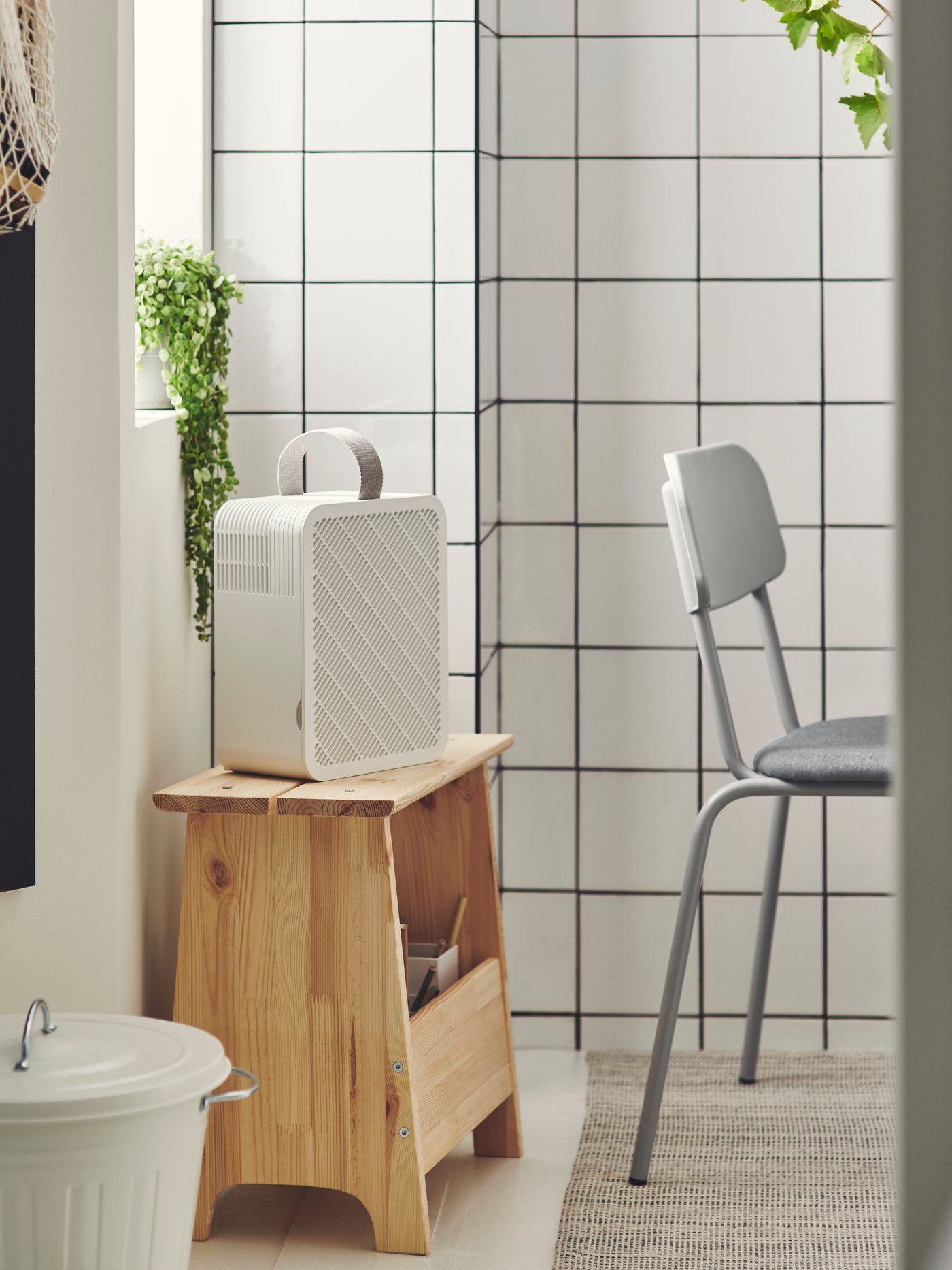 Čističky vzduchu a filtry IKEA stojí v místnosti vedle židle a stolu.