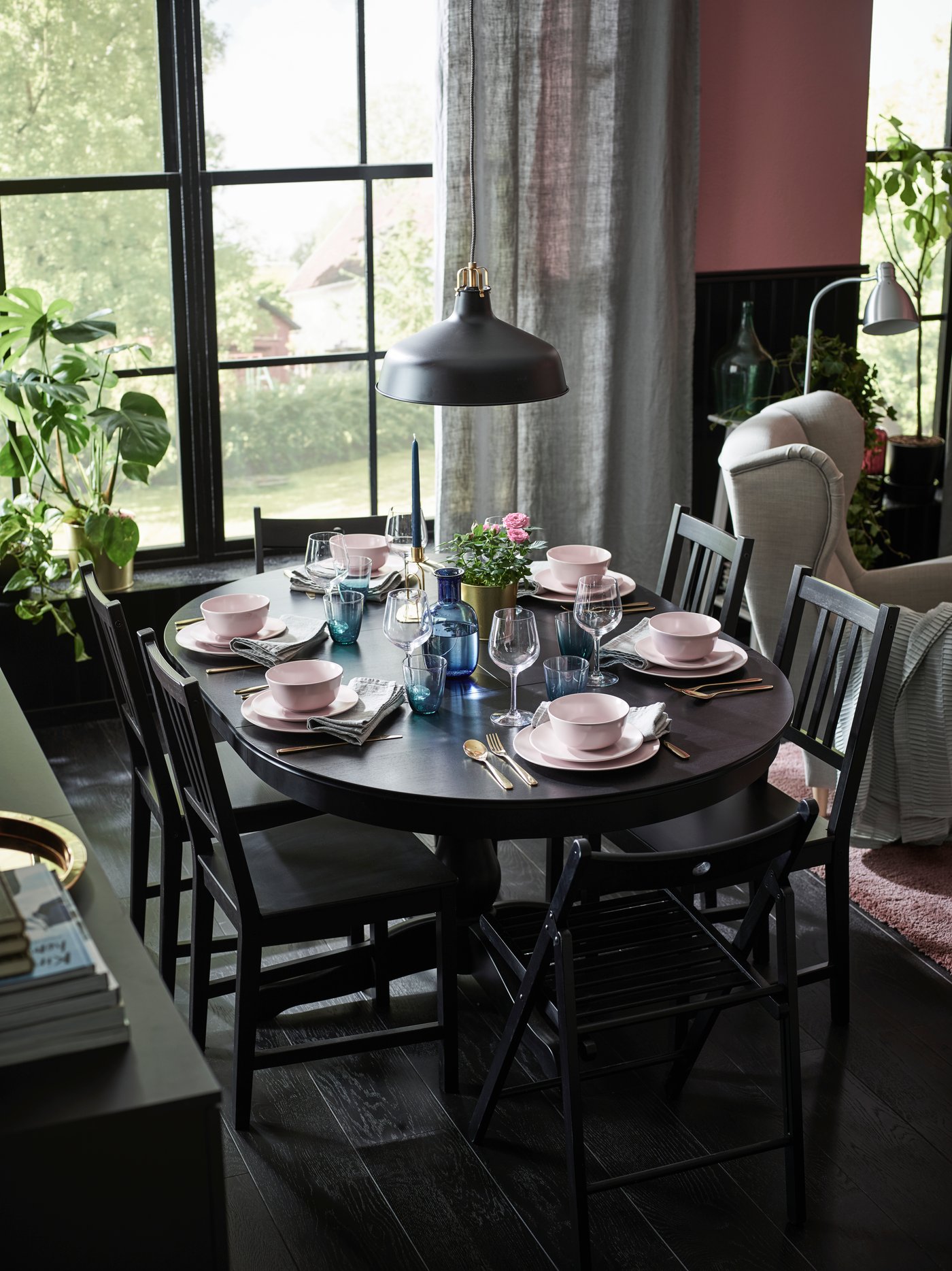 Comedor con mesa de comedor negra ovalada y 6 sillas. Detrás se ve una ventana con vista a un parque.