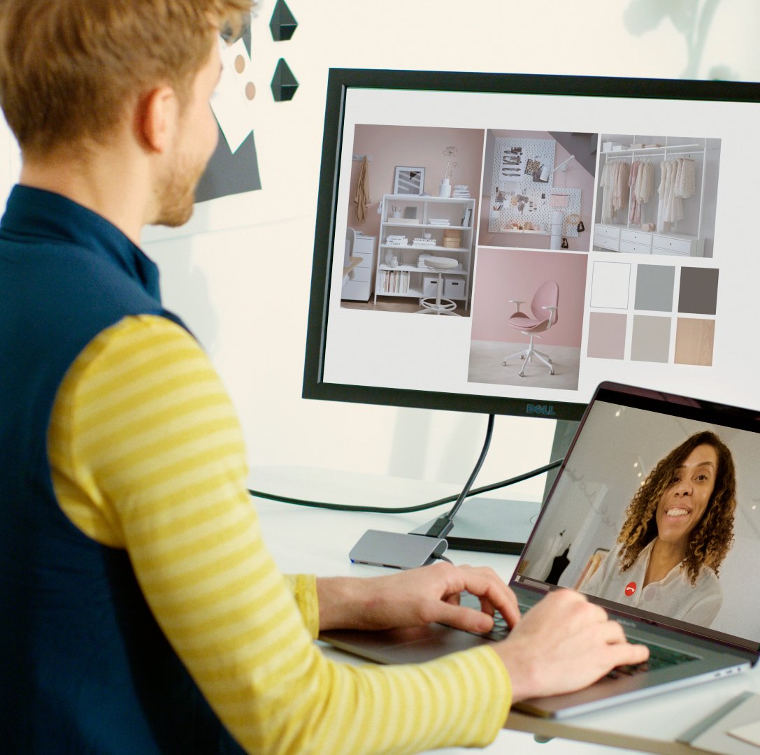 Person on video call at desk, viewing interior design ideas on monitor with pink-themed decor and color palette.