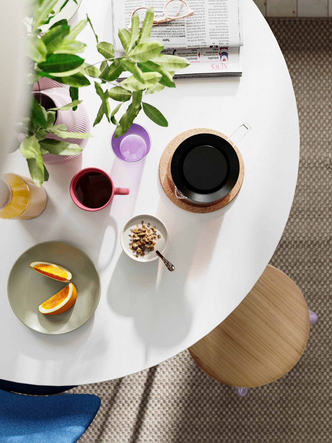 A DOCKSTA table set for breakfast with coffee, fruit, and bowls, alongside a stool and a potted plant in the background.