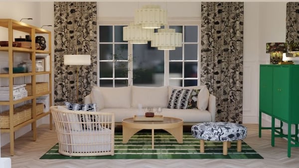 A furnished living room with patterned curtains, wooden shelves, a light sofa, woven seating, a wooden coffee table, a green storage cabinet, and a green patterned rug, styled with textiles and decorative elements.