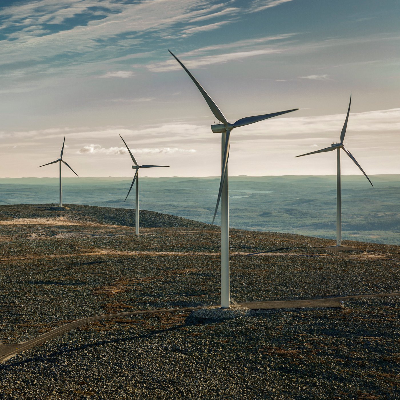 Nekoliko visokih vetroturbina u brdovitom krajoliku koristi energiju vetra pod vedrim nebom.