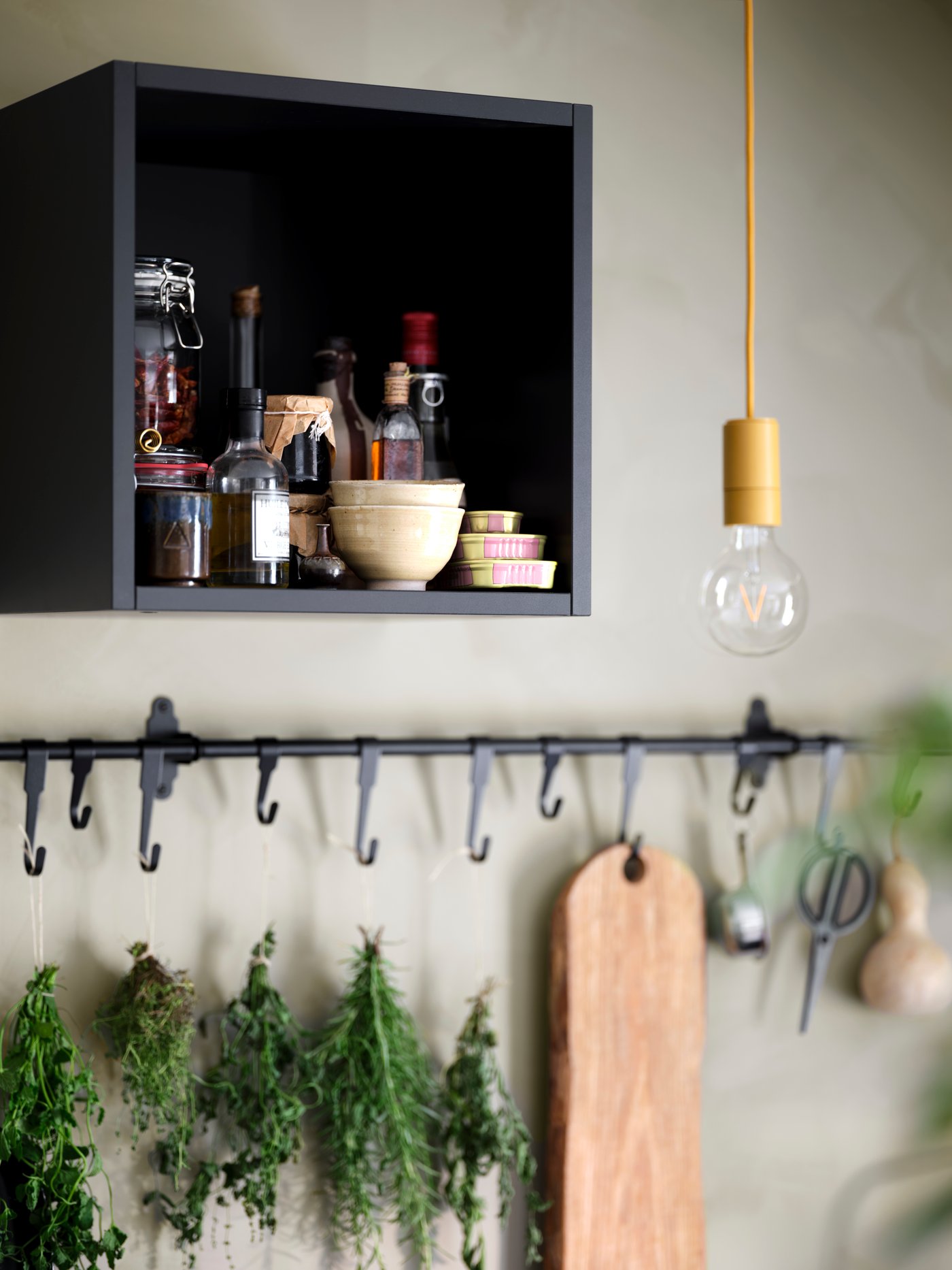 Close up of a black TUTEMO open cabinet with HULTARP rail and hook hanging on the wall below.