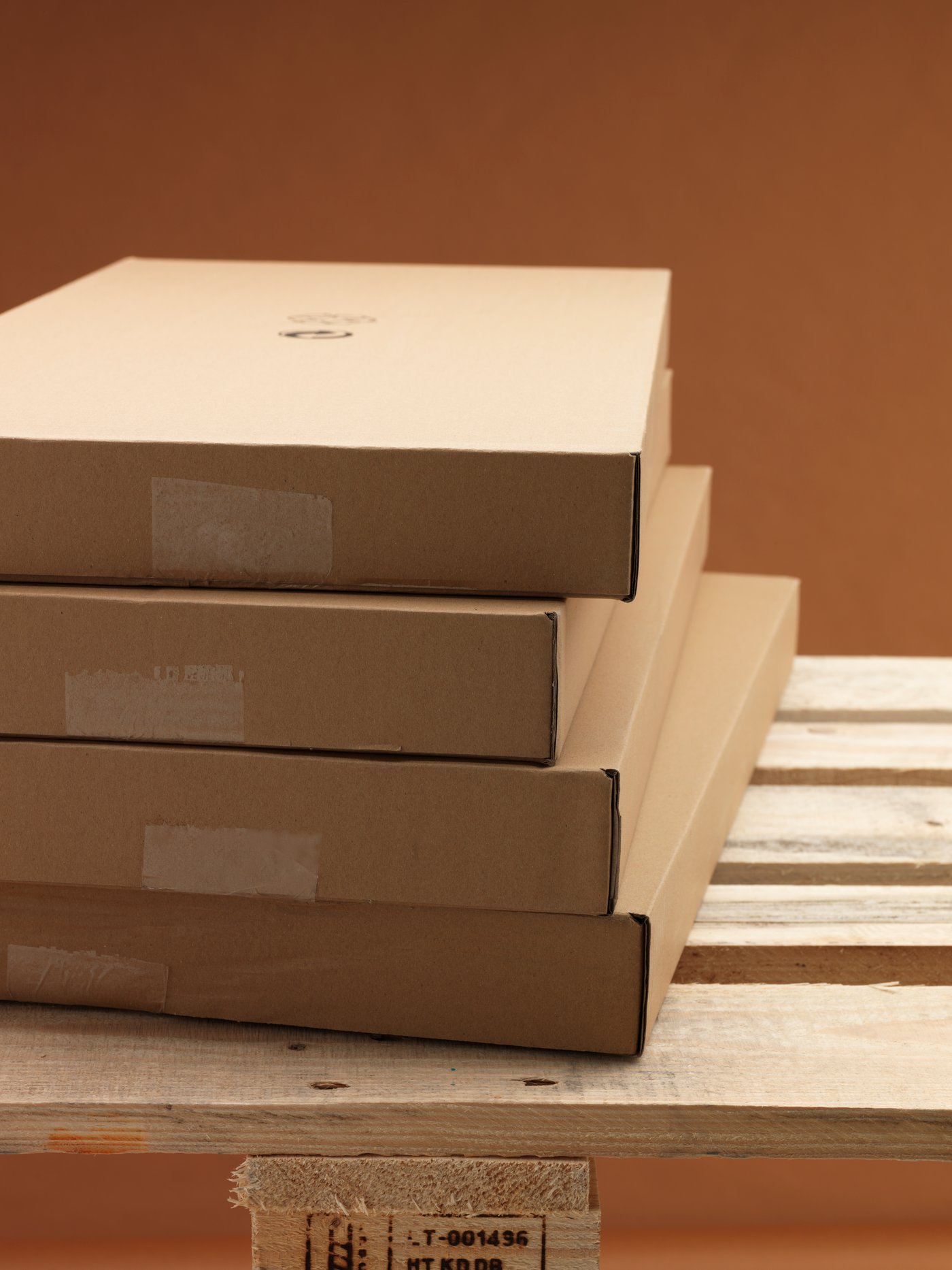 Četiri IKEA pljosnata pakovanja od recikliranog kartona uredno naslagana na drvenoj paleti za isporuku.