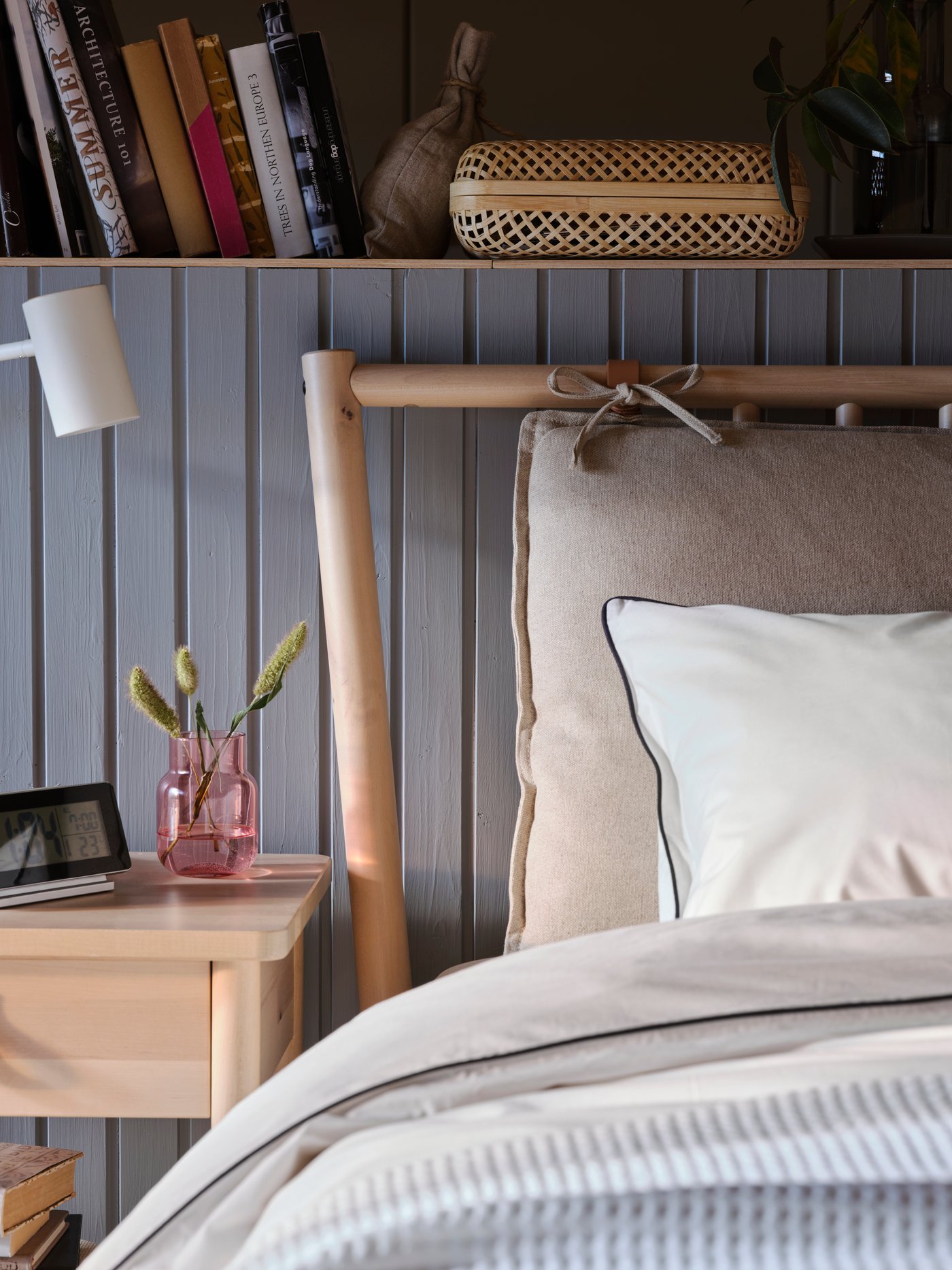 Un letto BJÖRKSNÄS davanti a una parete rivestita in legno con mensole incorporate, accanto a un comodino - IKEA