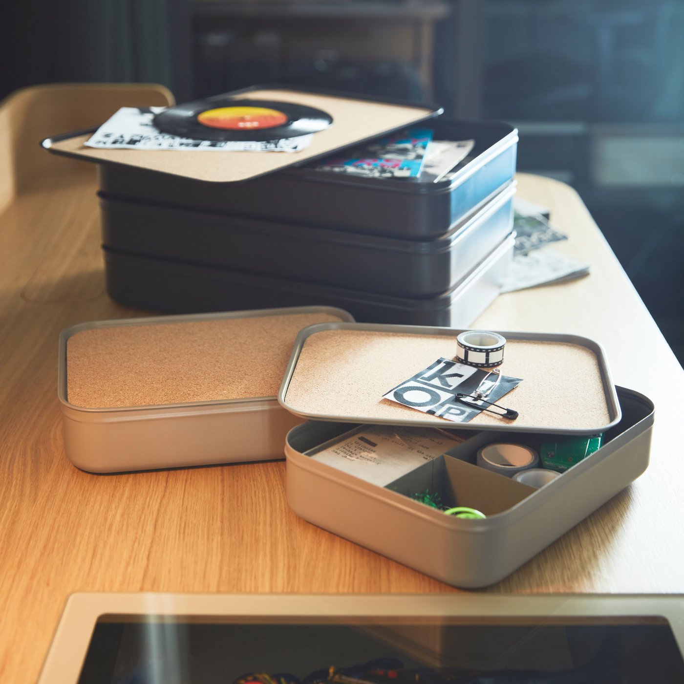 Multiple HARVMATTA boxes of two different kinds stacke and spread on the wooden desktop of a RIDSPÖ desk.