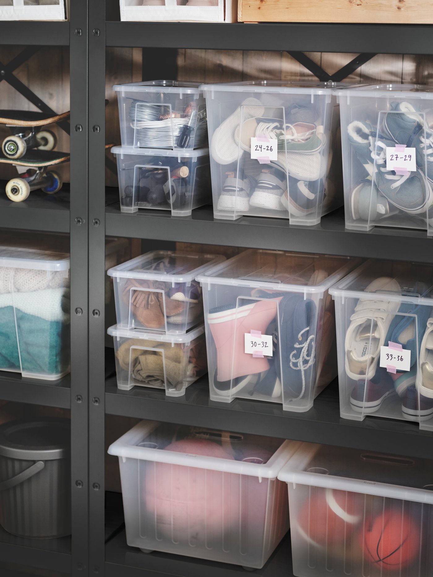 Two black BROR shelving units placed against a wall, holding different-sized SAMLA boxes with lid filled with shoes.