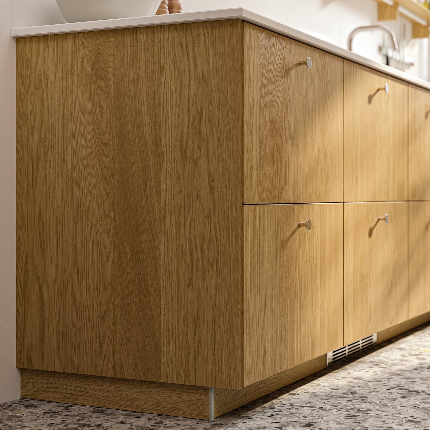 A closeup of METOD cabinets with fronts and cover panels in SINARP oak veneer and stainless steel-coloured KALERUM knobs.