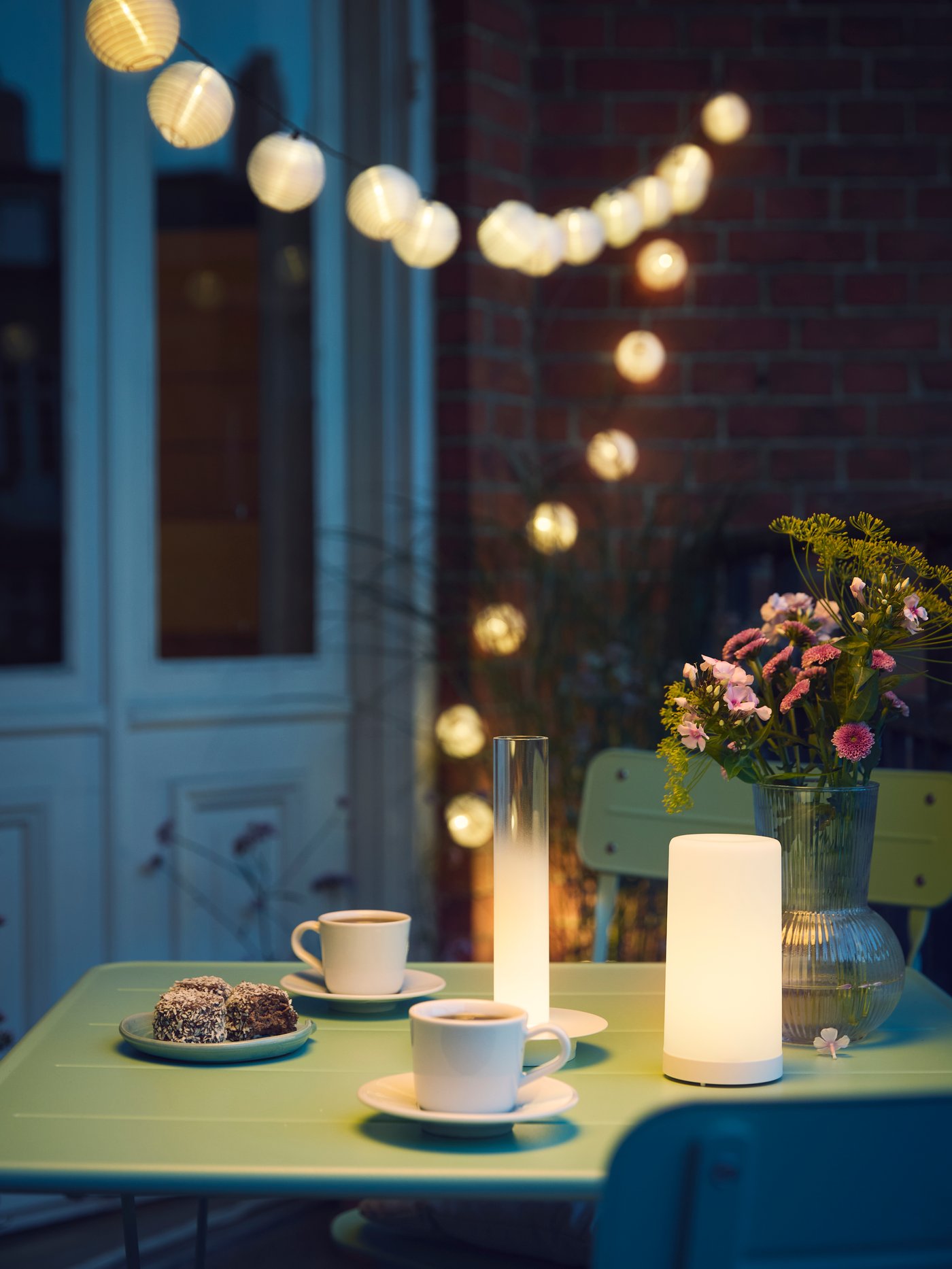 A light green outdoor SUNDSÖ folding chair outside and SOLVINDEN outdoor lamp