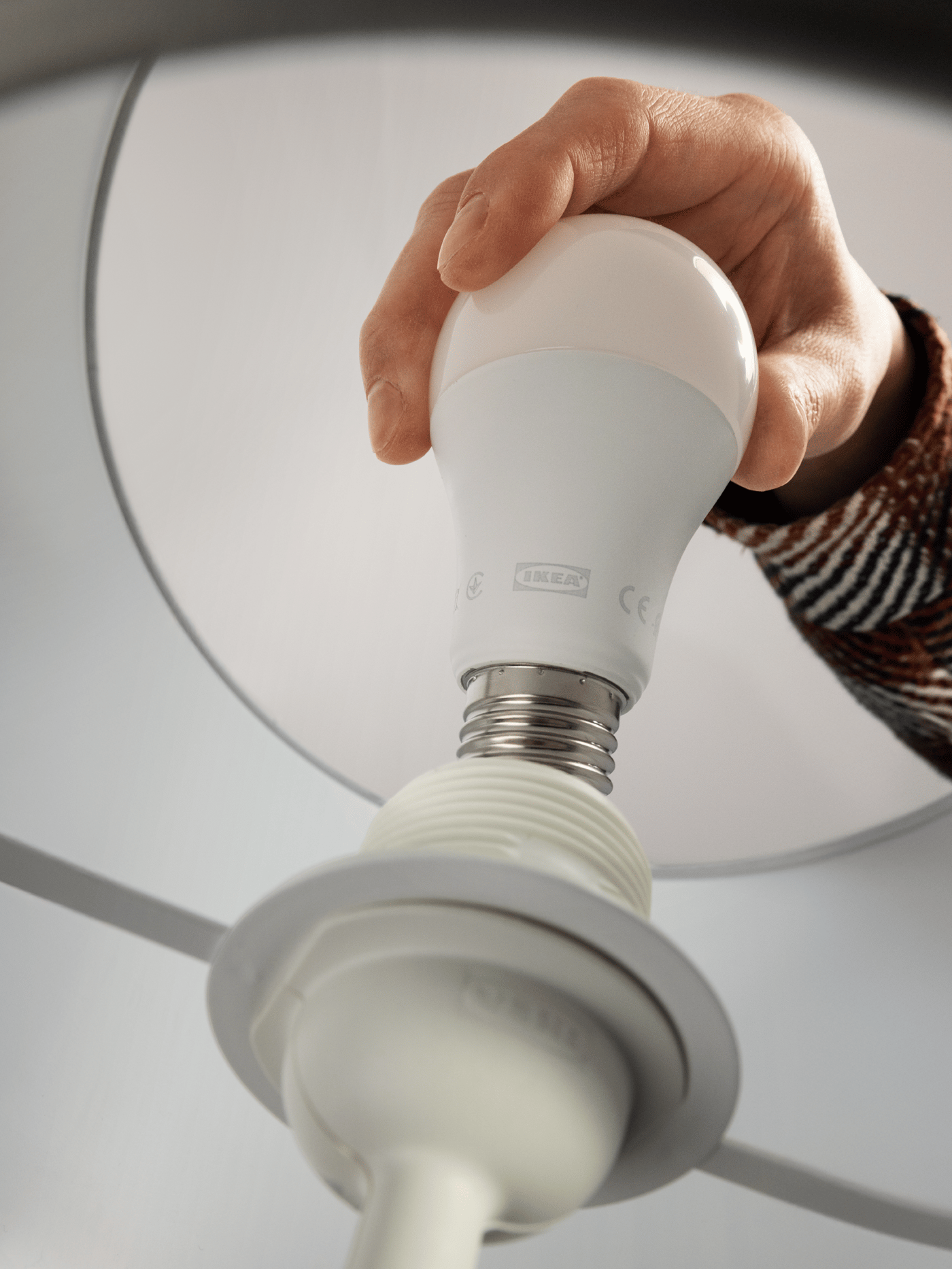 A person is installing a SOLHETTA light bulb into a lamp.