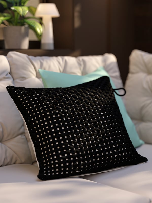 A patio with an outdoor corner sofa, grey-beige cushions and a pillow with a black outdoor/indoor TOFTÖ cushion cover.