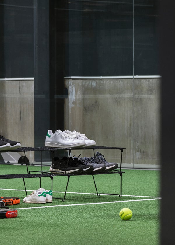 Närbild på en GREJIG skohylla stående på en padelbana. 