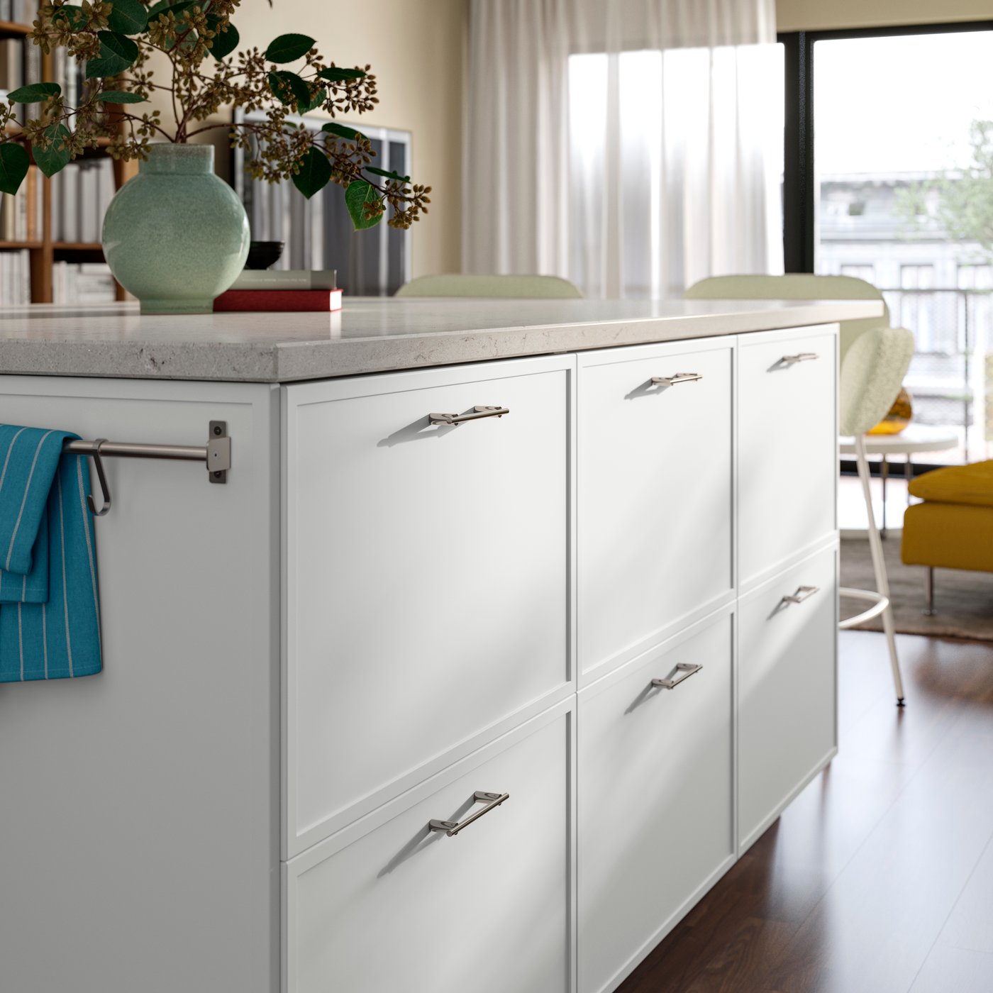 A close-up of a kitchen island with white ASPUDDEN drawer fronts featuring decorative flowers on the countertop.