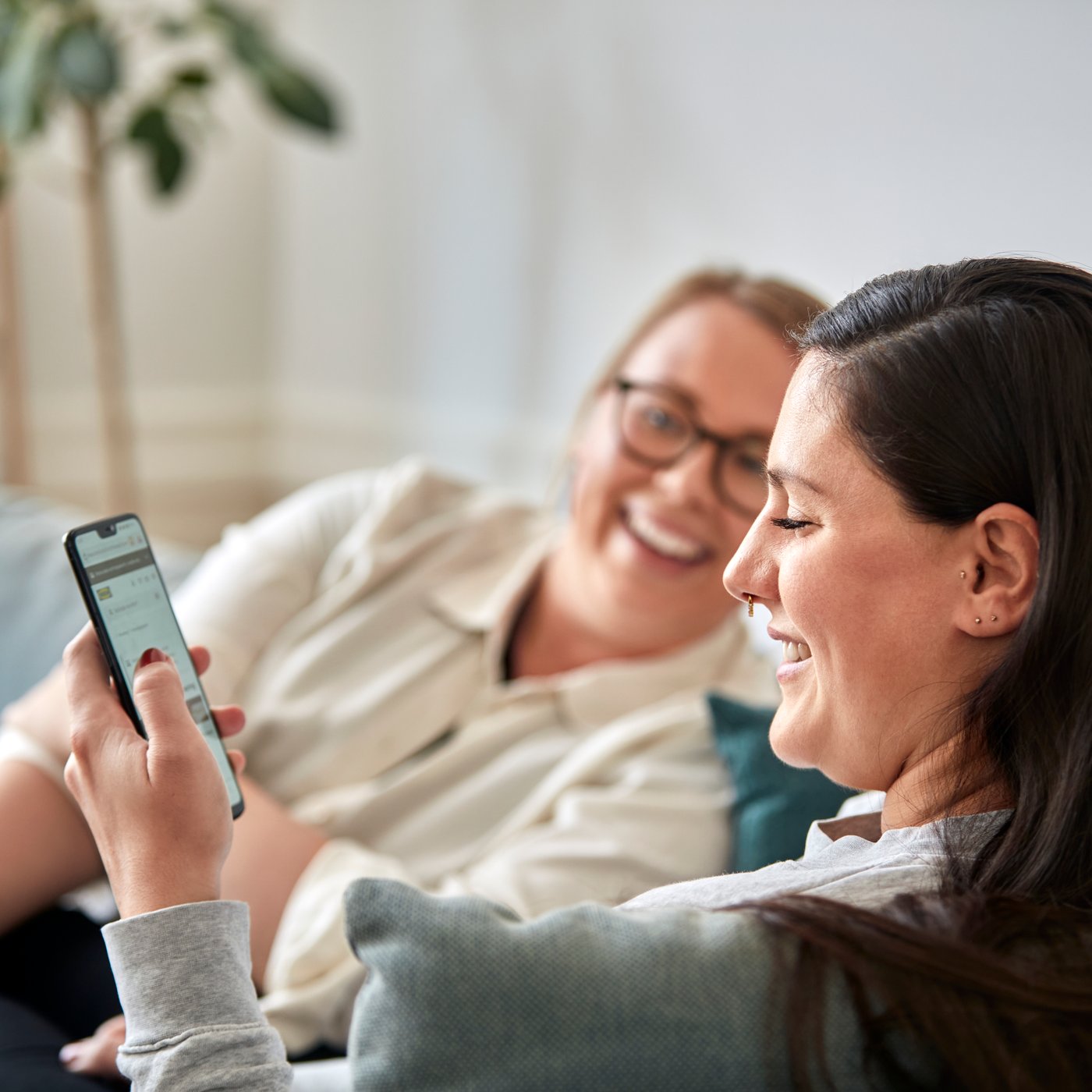 Two women smiling at a phone.
