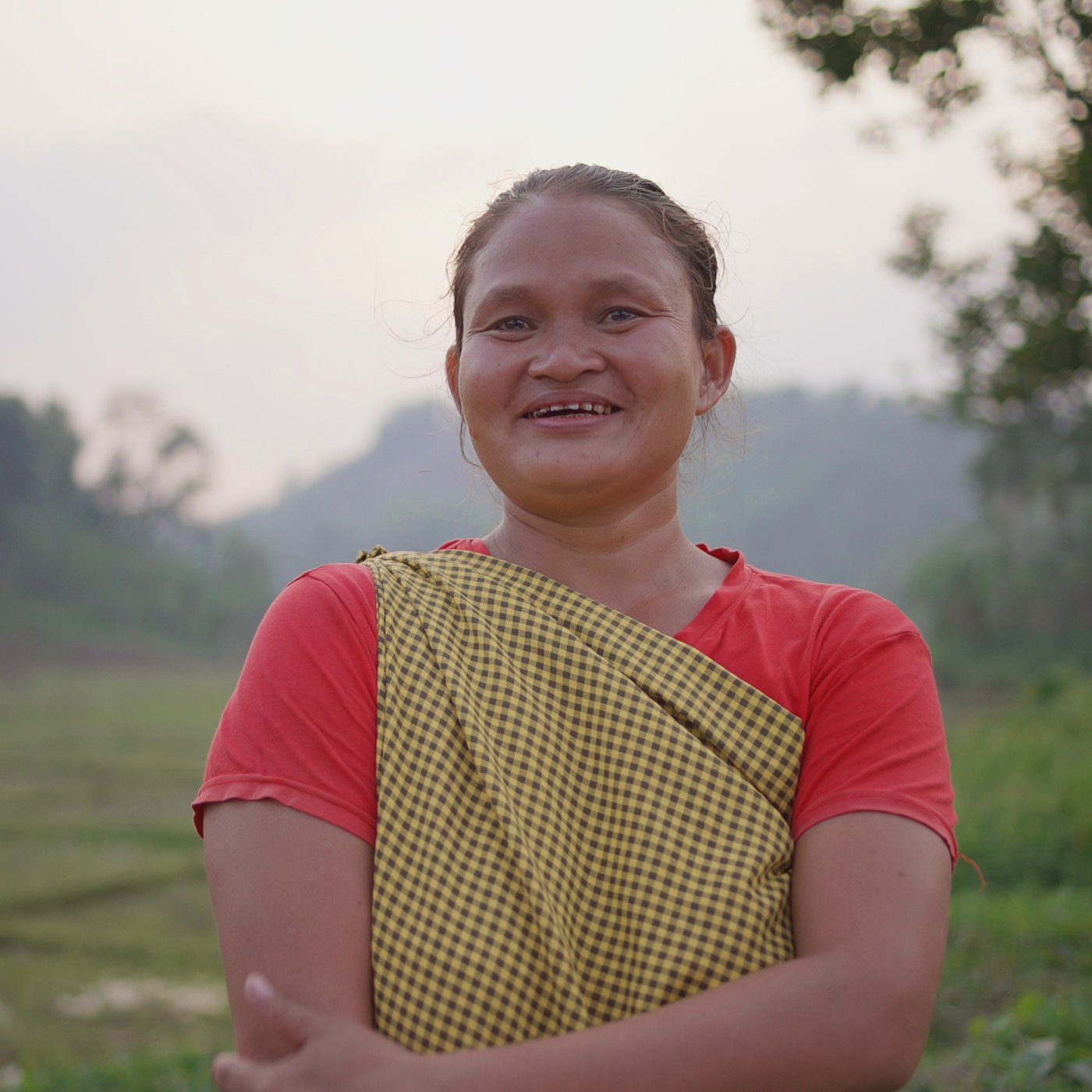 Women standing on a green field smiling in the sunset.